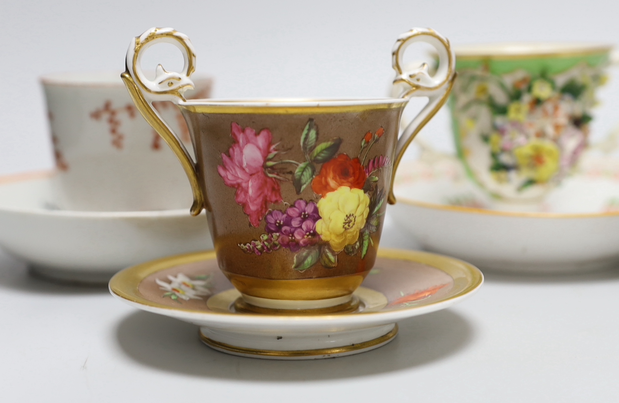A group of early 19th century English porcelain cups and various saucers to include a Spode two handled chocolate cup and saucer (10)